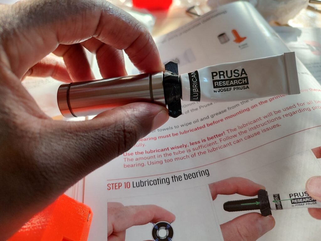 image of hand holding a bearing with lubricant tube inserted in one end.