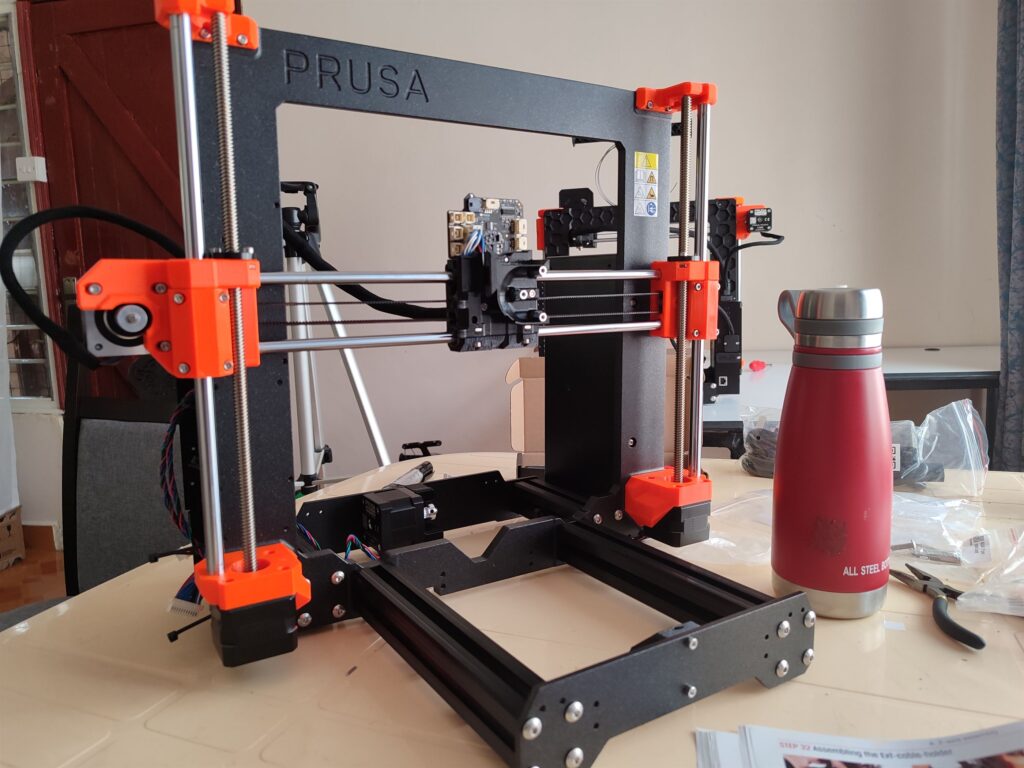 image of partially assembled Prusa MK4 3D printer next to red water bottle