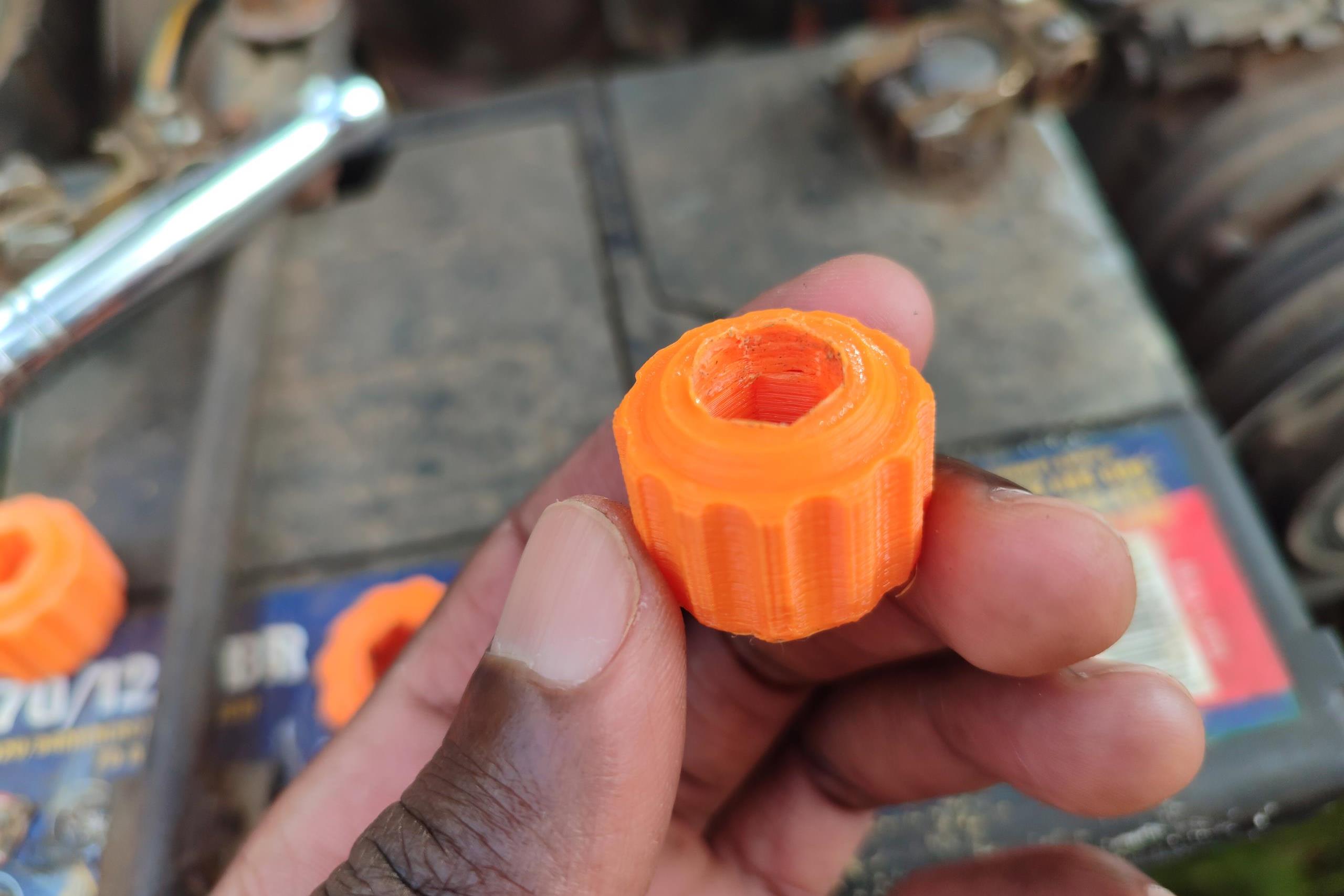 Hand holding orange 3D printed part