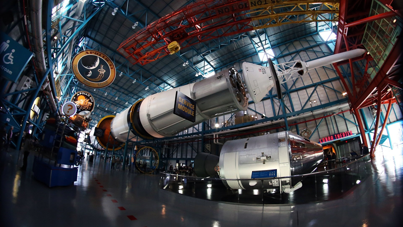 NASA spacecraft and space module on display inside building.